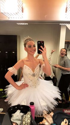 a woman taking a selfie in front of a mirror wearing a white tutu