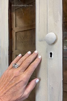 a woman's hand is holding onto the door knob on an old wooden door