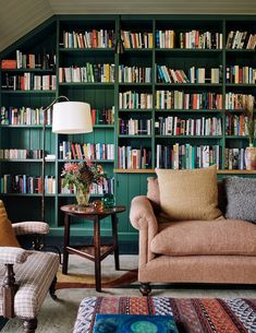 a living room filled with furniture and lots of bookshelves covered in green bookcases