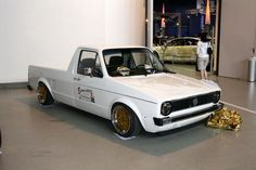 a white pick up truck with gold rims parked in front of a car showroom