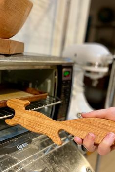 a person holding a wooden spatula in front of an oven