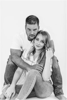 a man and woman sitting next to each other on the floor in black and white