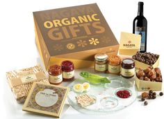 an assortment of organic gifts in a box with wine and crackers next to it