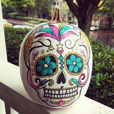 a painted pumpkin sitting on top of a white fence