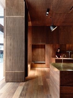 a person sitting in a room with wooden walls and flooring on the other side