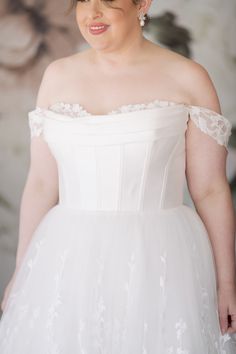 a woman in a white dress is posing for a photo with her hands on her hips