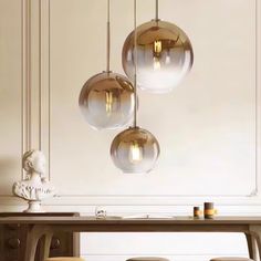 three glass balls hanging from the ceiling above a dining room table with four stools