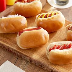 four hot dogs on buns with ketchup and mustard