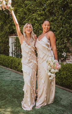 two bridesmaids holding bouquets in their hands and posing for the camera outside