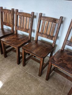 three wooden chairs sitting next to each other on a tile floor in front of a wall