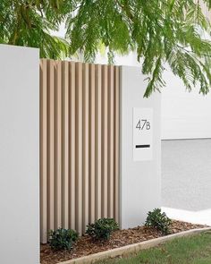 a tall white building sitting next to a lush green tree