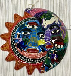 a colorful sun ornament hanging on a wooden wall