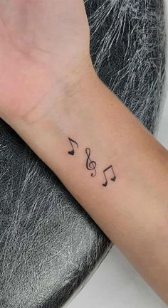 a woman's wrist with musical notes tattooed on the left side of her arm