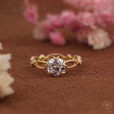 a diamond ring sitting on top of a brown surface next to flowers and shells in the background