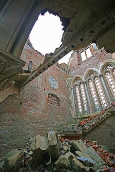 the interior of an abandoned building with rubble and debris on the ground, looking up at a clock tower