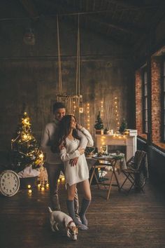 a man and woman standing next to each other in front of a christmas tree with lights