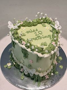 a green cake with white flowers and butterflies on it