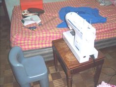 a sewing machine sitting on top of a wooden table next to a small child's bed