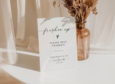 a vase filled with dried flowers next to a sign that says freshen up please help yourself