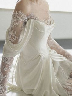 a woman in a white wedding dress sitting on the floor with her hands behind her head