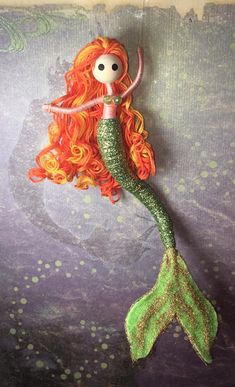 a mermaid doll with orange hair and green tail