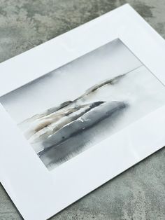 a white frame sitting on top of a cement floor next to a black and white painting