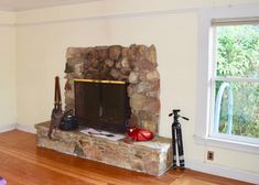 a living room with a stone fireplace and hard wood flooring