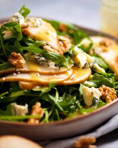 a salad with cheese and spinach in a brown bowl on a gray table cloth