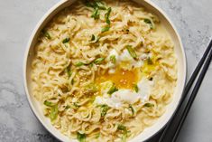 a bowl of noodles with an egg on top and chopsticks next to it