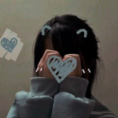 a woman covering her face with two hearts drawn on the back of her head and hands