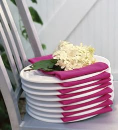 a stack of plates with flowers on them sitting on a table next to a chair