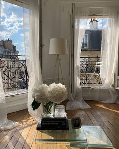 a living room filled with furniture and windows covered in white curtained draping