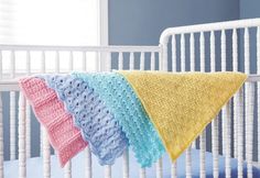 three crocheted blankets are hanging from a white crib