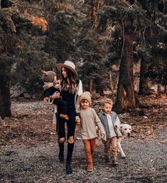 a woman and two children walking in the woods with their dog on a fall day