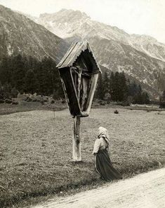 an old black and white photo of a woman standing next to a cross