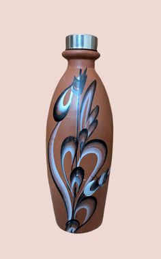 a brown vase with blue and white designs on it's sides, against a pink background