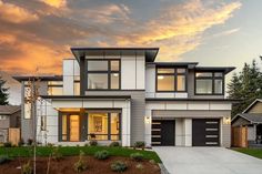 a two story house with lots of windows on the front and side of it at sunset