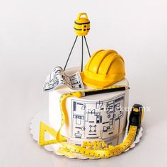 a cake with construction equipment on top of it and measuring tape around the edges,