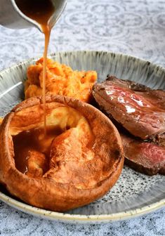 steak, mashed potatoes and gravy on a plate with sauce being drizzled over it