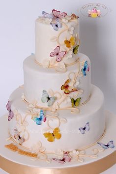 a three tiered wedding cake with butterflies on it