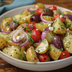 a white bowl filled with potatoes, onions and red onion on top of a wooden table