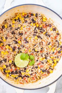 mexican rice and black beans in a skillet with a lime slice on the side