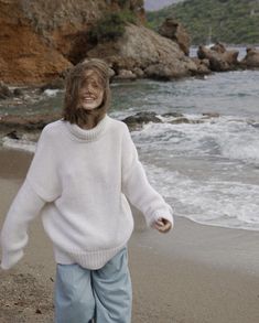 a woman walking on the beach next to the ocean