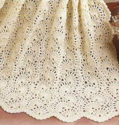 a white crocheted blanket sitting on top of a wooden table next to a potted plant