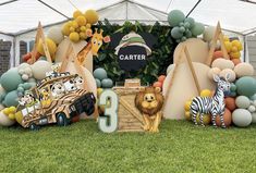 an animal themed birthday party with balloons and decorations on the grass, including cars, zebras, and giraffes