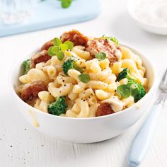 a white bowl filled with macaroni and broccoli on top of a table