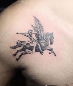 the back of a man's shoulder with a tattoo of a horse and rider on it