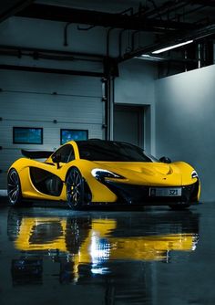 a yellow sports car is parked in an empty garage with its doors open and lights on