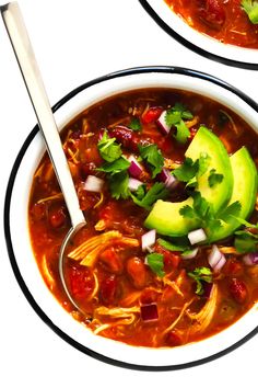 a bowl of chili soup with avocado and cilantro