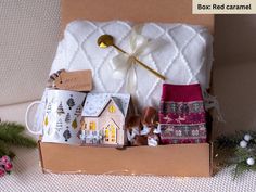 a box filled with coffee cups and miniature houses on top of a table next to christmas decorations